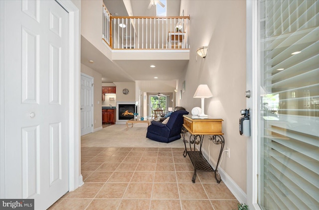 tiled foyer with ceiling fan and a towering ceiling