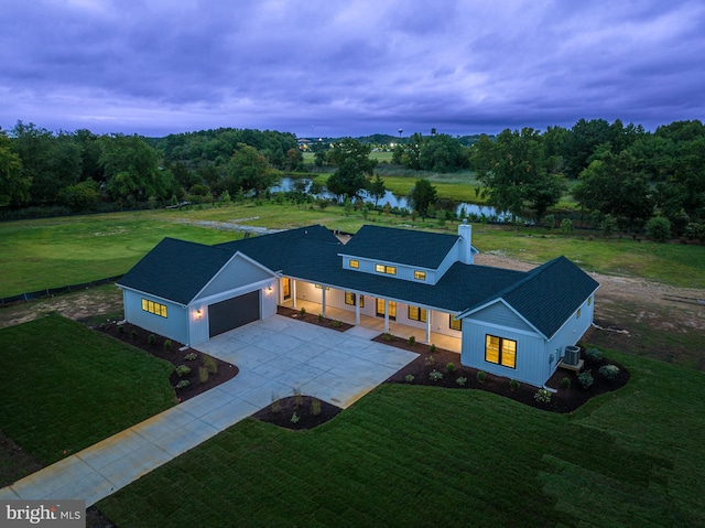 view of front of home with driveway, a water view, an attached garage, a front lawn, and central AC