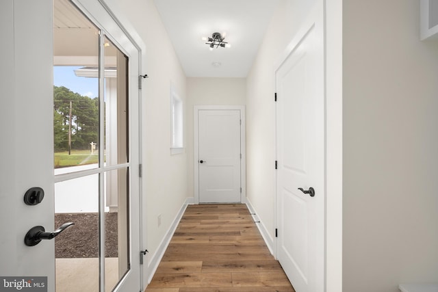 corridor with light wood-style floors and baseboards