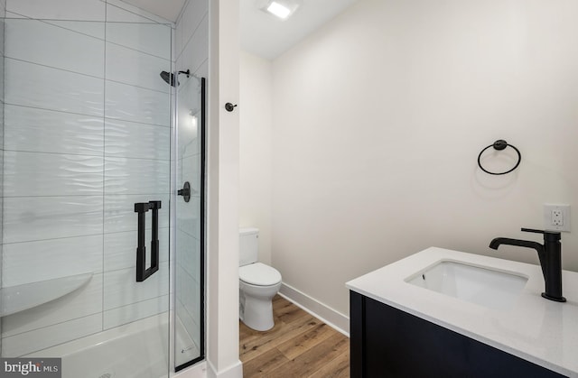 bathroom with a stall shower, toilet, and wood finished floors