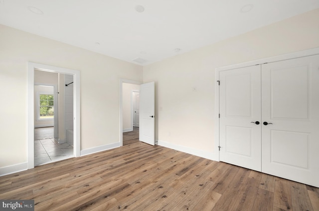 unfurnished bedroom with a closet, baseboards, and hardwood / wood-style flooring