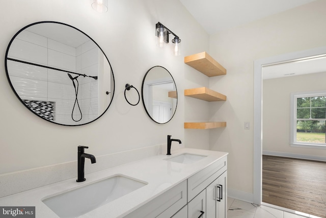 full bath featuring double vanity, marble finish floor, baseboards, and a sink