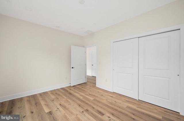 unfurnished bedroom with a closet, light wood-type flooring, and baseboards