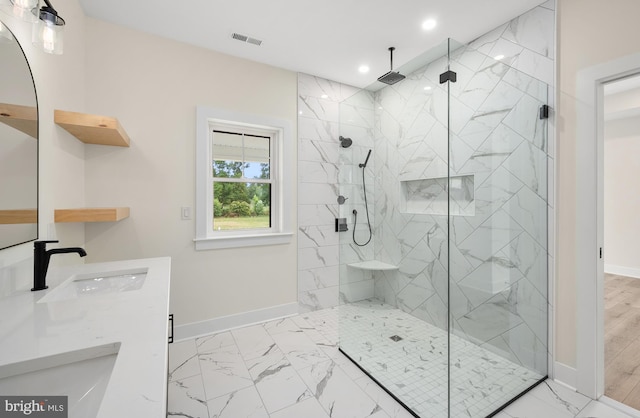 bathroom featuring a sink, visible vents, baseboards, marble finish floor, and a marble finish shower