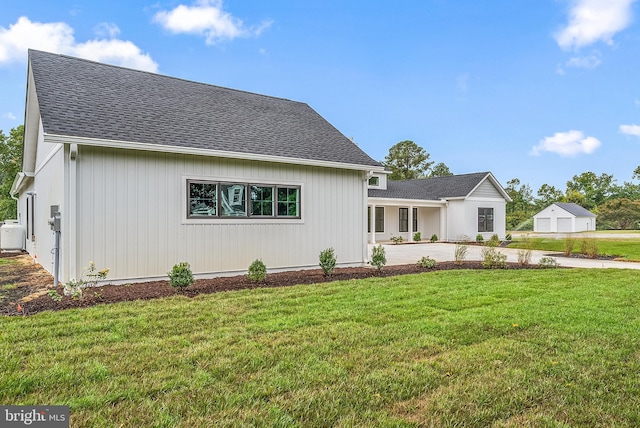 view of front of home with a shingled roof and a front lawn