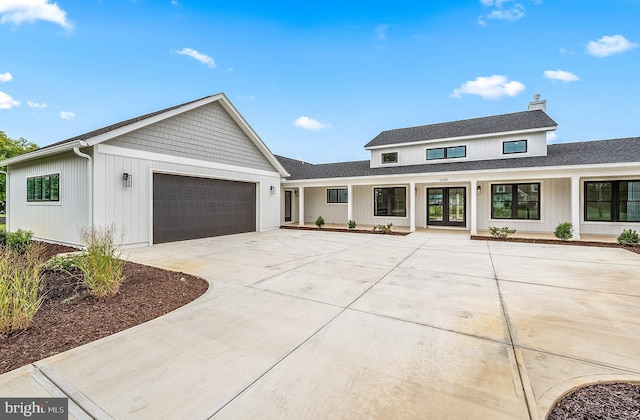 modern farmhouse style home featuring an attached garage, concrete driveway, and french doors