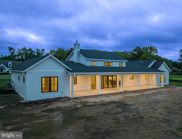 rear view of house featuring roof with shingles, a patio, a chimney, and central air condition unit