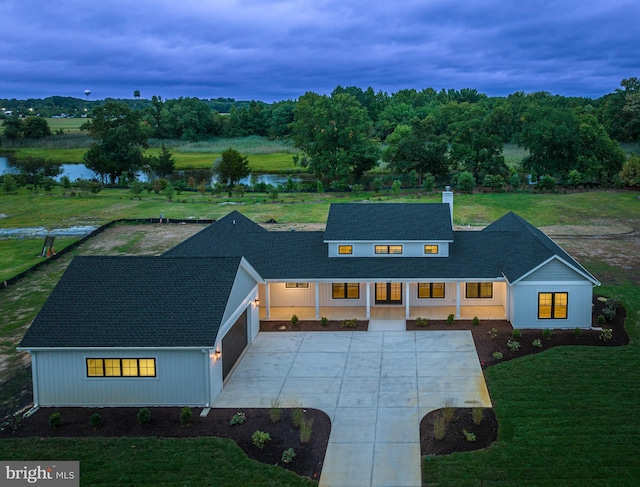 view of front facade with a porch, a front yard, concrete driveway, and a water view