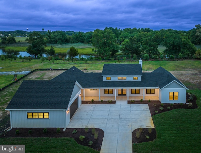 view of front of house with a garage, a yard, and a water view