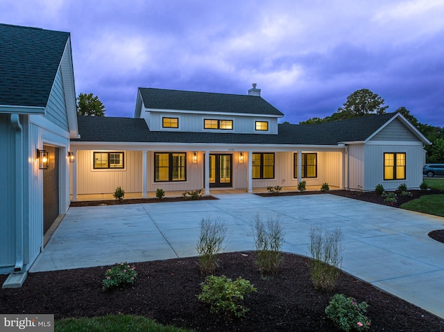 modern farmhouse with covered porch, roof with shingles, and a chimney