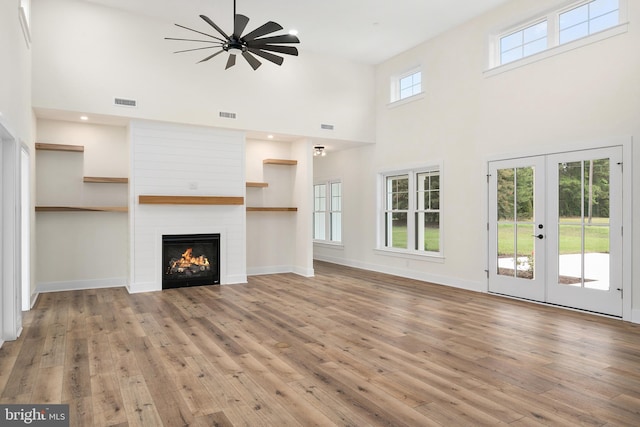 unfurnished living room featuring a fireplace, a ceiling fan, visible vents, baseboards, and light wood finished floors