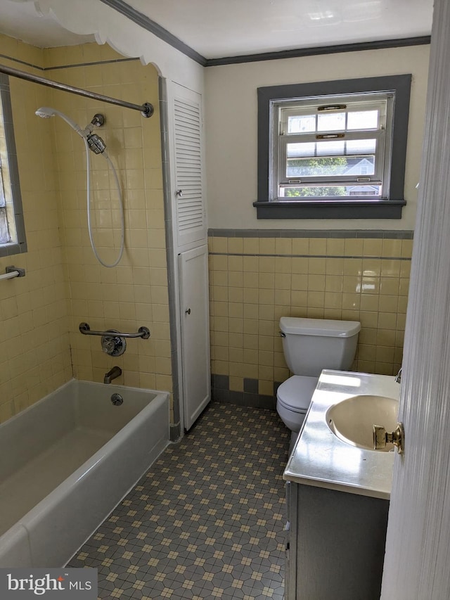 full bathroom featuring vanity, tiled shower / bath combo, tile walls, crown molding, and toilet