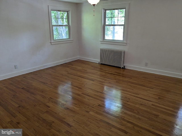 unfurnished room with dark hardwood / wood-style flooring, radiator heating unit, and a healthy amount of sunlight