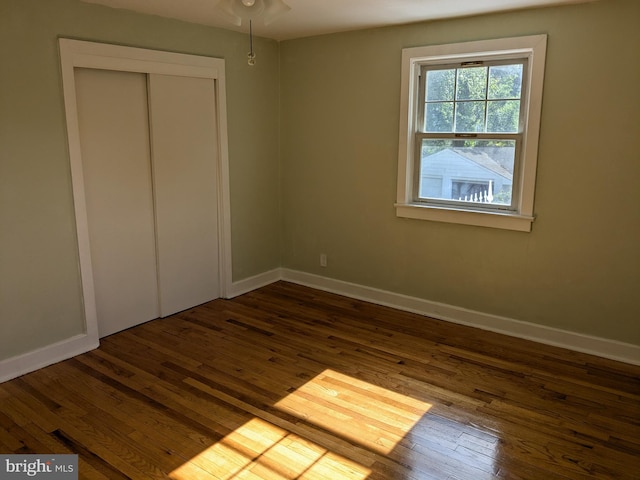 unfurnished bedroom with dark hardwood / wood-style floors and a closet