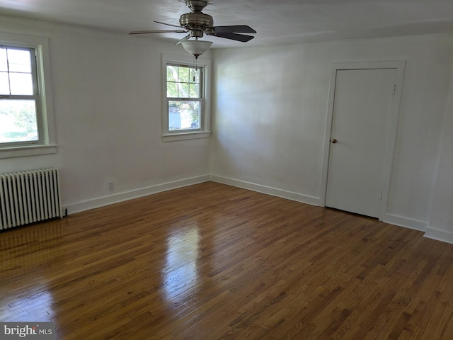 spare room featuring ceiling fan, dark hardwood / wood-style flooring, and radiator heating unit