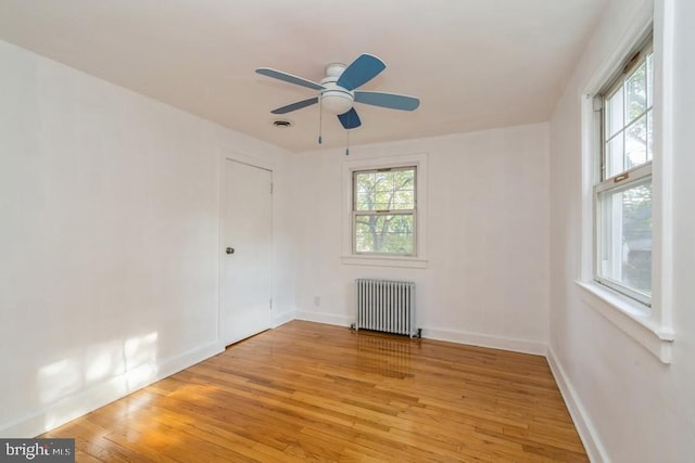 unfurnished room featuring light hardwood / wood-style floors, radiator, and ceiling fan