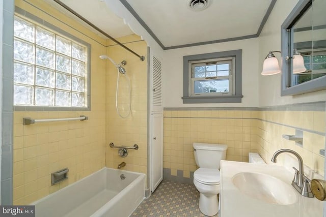 full bathroom featuring tile walls, tiled shower / bath combo, tile patterned floors, vanity, and toilet