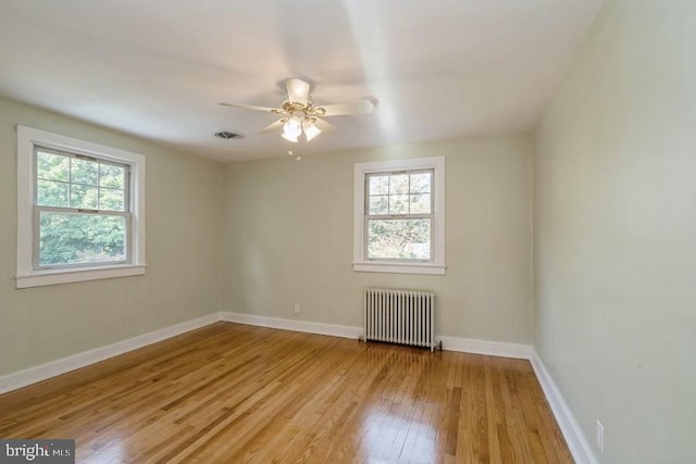 unfurnished room featuring radiator heating unit, ceiling fan, and light hardwood / wood-style flooring