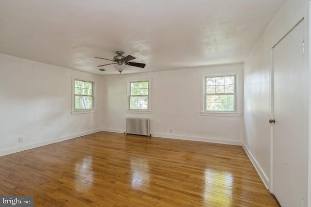 spare room with light hardwood / wood-style floors, ceiling fan, and radiator heating unit