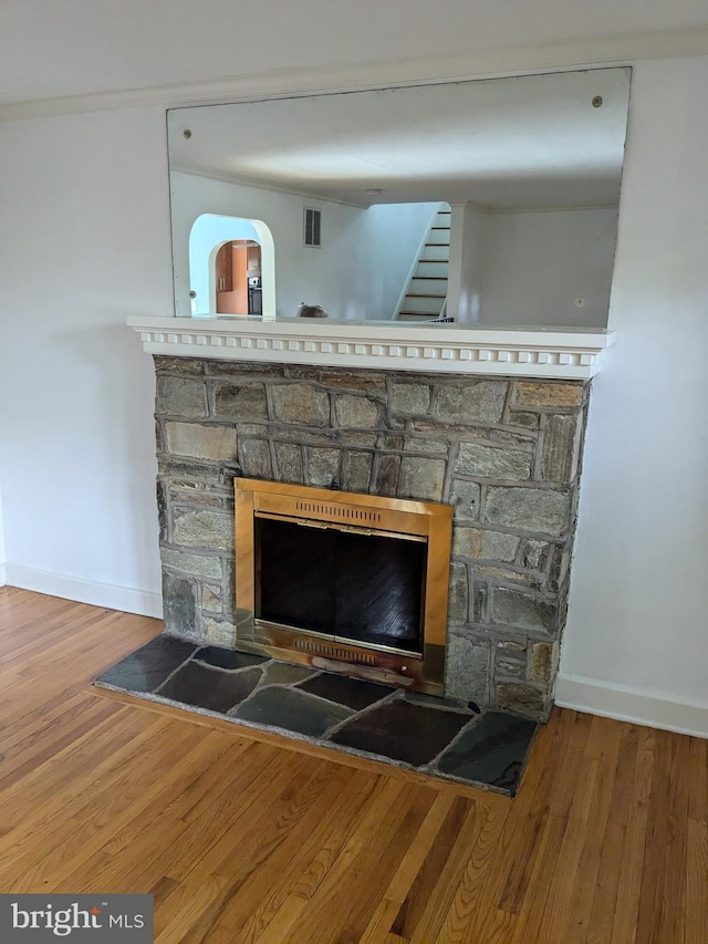 room details with wood-type flooring, crown molding, and a stone fireplace