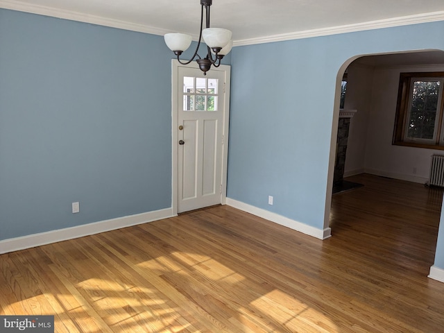 spare room featuring ornamental molding, an inviting chandelier, hardwood / wood-style flooring, and radiator heating unit