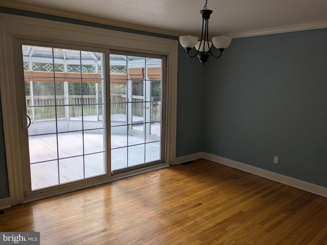 spare room with an inviting chandelier, light wood-type flooring, and crown molding