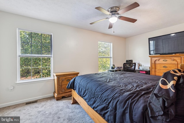 carpeted bedroom with baseboards, visible vents, ceiling fan, and a textured ceiling