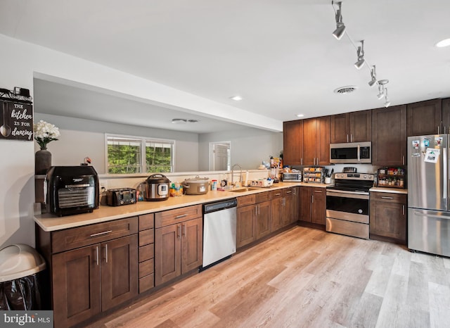 kitchen with rail lighting, sink, appliances with stainless steel finishes, and light hardwood / wood-style floors