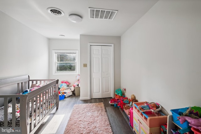 bedroom featuring a nursery area, wood-type flooring, and a closet