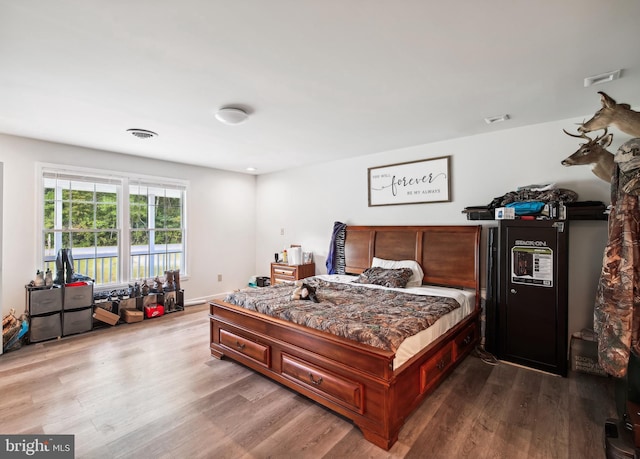 bedroom featuring visible vents, baseboards, and wood finished floors