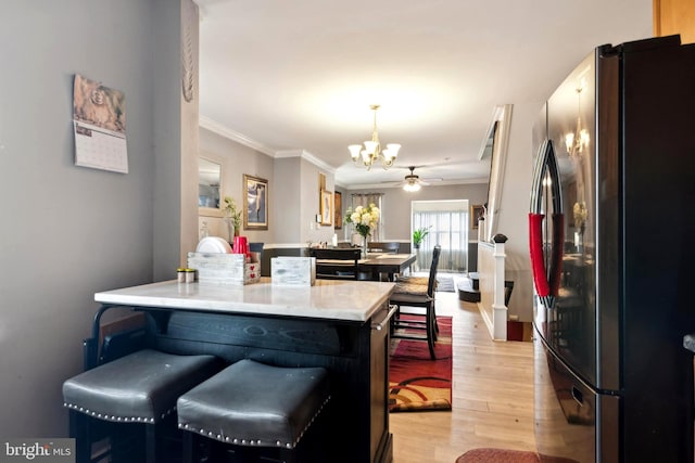 kitchen featuring ornamental molding, stainless steel refrigerator, light wood-type flooring, and a chandelier