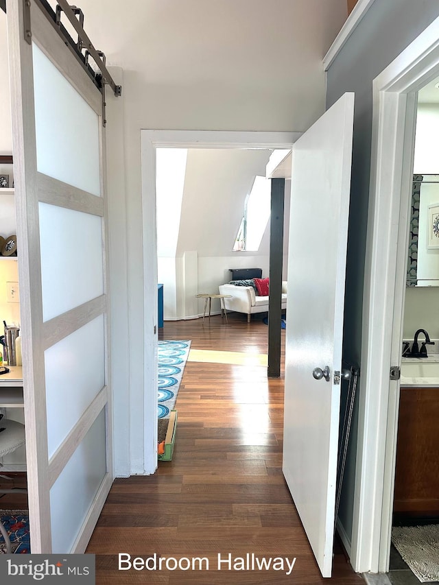 corridor with sink, dark wood-type flooring, and a barn door