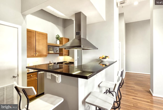 kitchen with island range hood, light hardwood / wood-style flooring, a kitchen bar, and kitchen peninsula