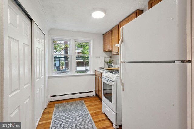 kitchen featuring light hardwood / wood-style flooring, baseboard heating, and white appliances