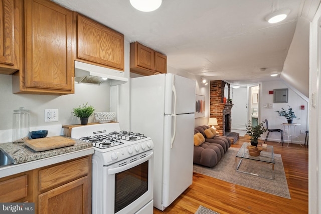 kitchen featuring light wood-style flooring, under cabinet range hood, white appliances, brown cabinetry, and light countertops