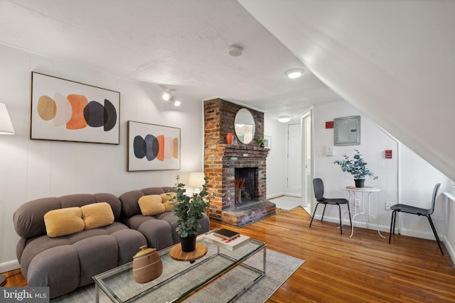 living area with electric panel, baseboards, wood finished floors, and a fireplace