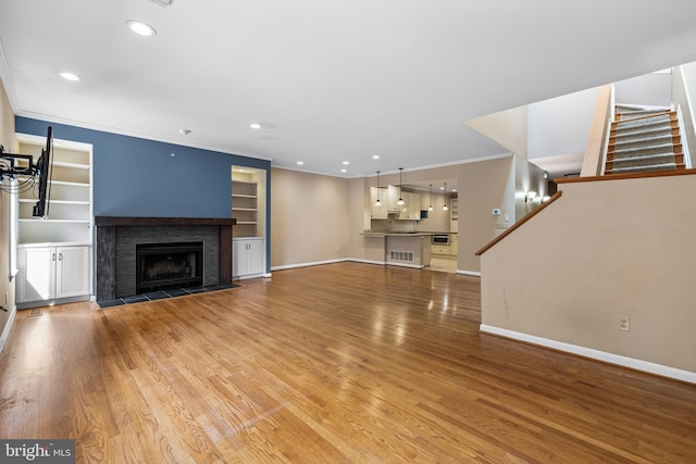 unfurnished living room with wood-type flooring and ornamental molding