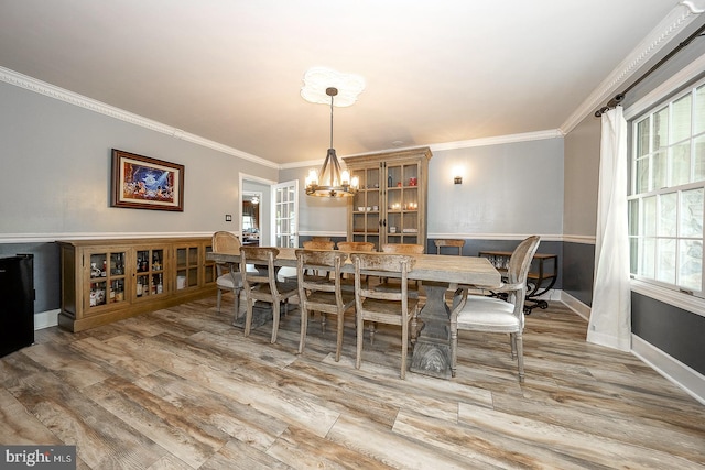 dining room featuring light hardwood / wood-style flooring, a chandelier, plenty of natural light, and crown molding