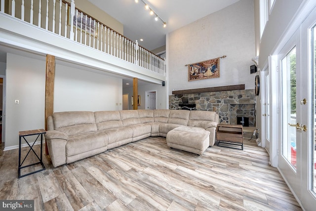 living room featuring a fireplace, track lighting, a high ceiling, and light wood-type flooring