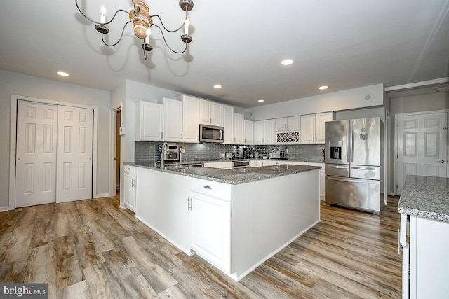 kitchen with stainless steel appliances, decorative backsplash, light hardwood / wood-style flooring, and white cabinets