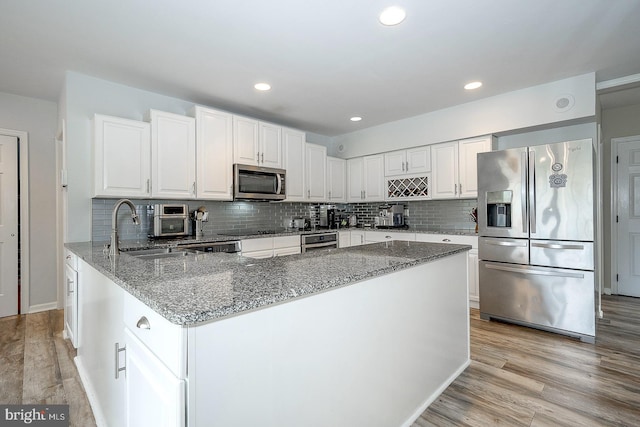 kitchen featuring light stone countertops, sink, appliances with stainless steel finishes, and light wood-type flooring