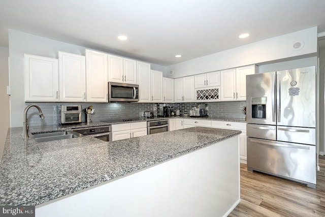 kitchen featuring white cabinets, light wood-type flooring, dark stone counters, sink, and stainless steel appliances