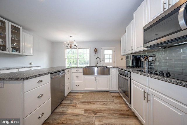 kitchen with appliances with stainless steel finishes, kitchen peninsula, light wood-type flooring, and white cabinets