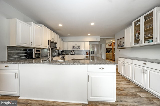 kitchen featuring appliances with stainless steel finishes, kitchen peninsula, white cabinets, and dark stone counters