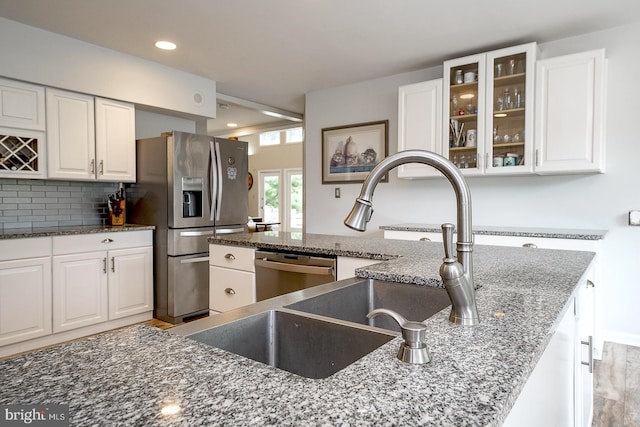 kitchen featuring white cabinets, stainless steel appliances, and dark stone counters