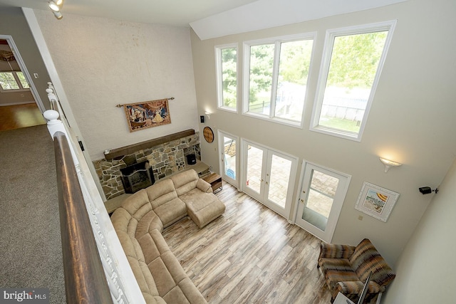 living room featuring high vaulted ceiling, a healthy amount of sunlight, light hardwood / wood-style flooring, and a fireplace