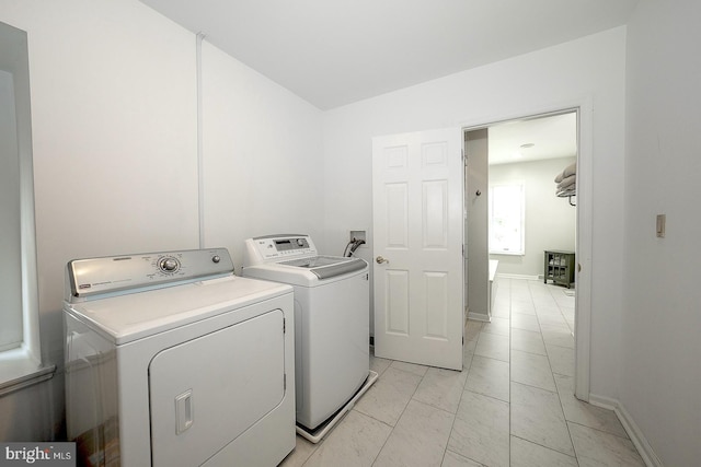 laundry area with washer and clothes dryer and light tile patterned floors