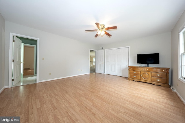 unfurnished bedroom with ceiling fan, multiple windows, and light wood-type flooring