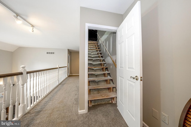 staircase featuring vaulted ceiling, carpet, and track lighting