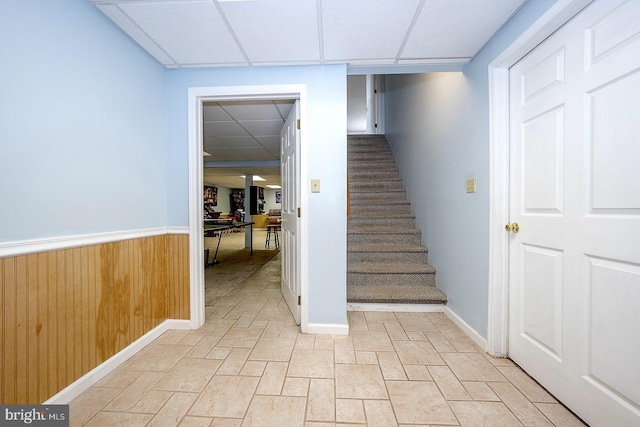 stairway with a drop ceiling and wooden walls